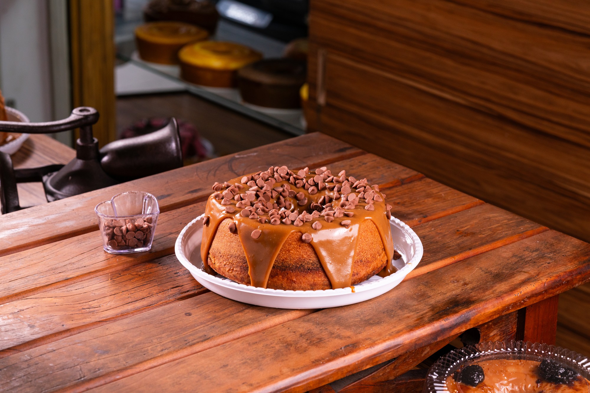 Bolo com cobertura de chocolate e confeitos sobre mesa de madeira